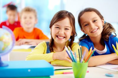 Smiling primary school students writing at their desks