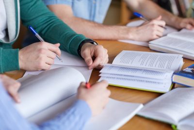 Students writing in exercise books around a table